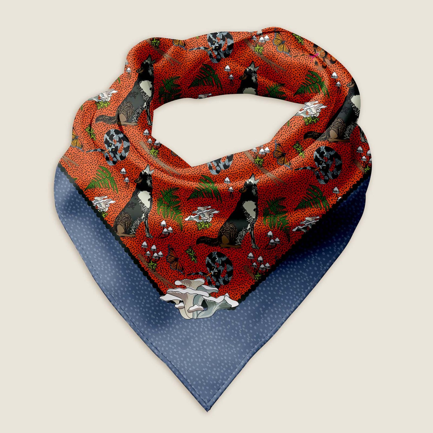Wolf bandana scarf on an ivory background. This is an image of the Wild Wolf bandana scarf styled into a wrap showing the hand-drawn artwork of howling wolves, curly snakes, moss, mushrooms, ferns, and butterflies on a red background with a warm purple border with a white dot pattern.