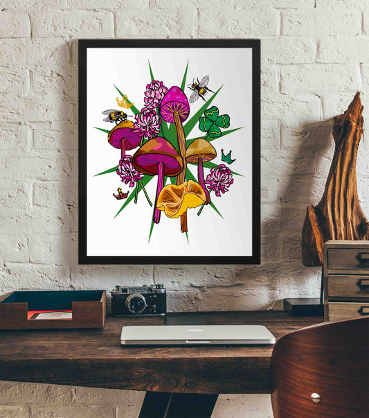 This photo shows the framed Queen's Favor art print hanging on a white brick wall. Below it, there is a wood. The desk has a camera, laptop, and wood sculpture on it.