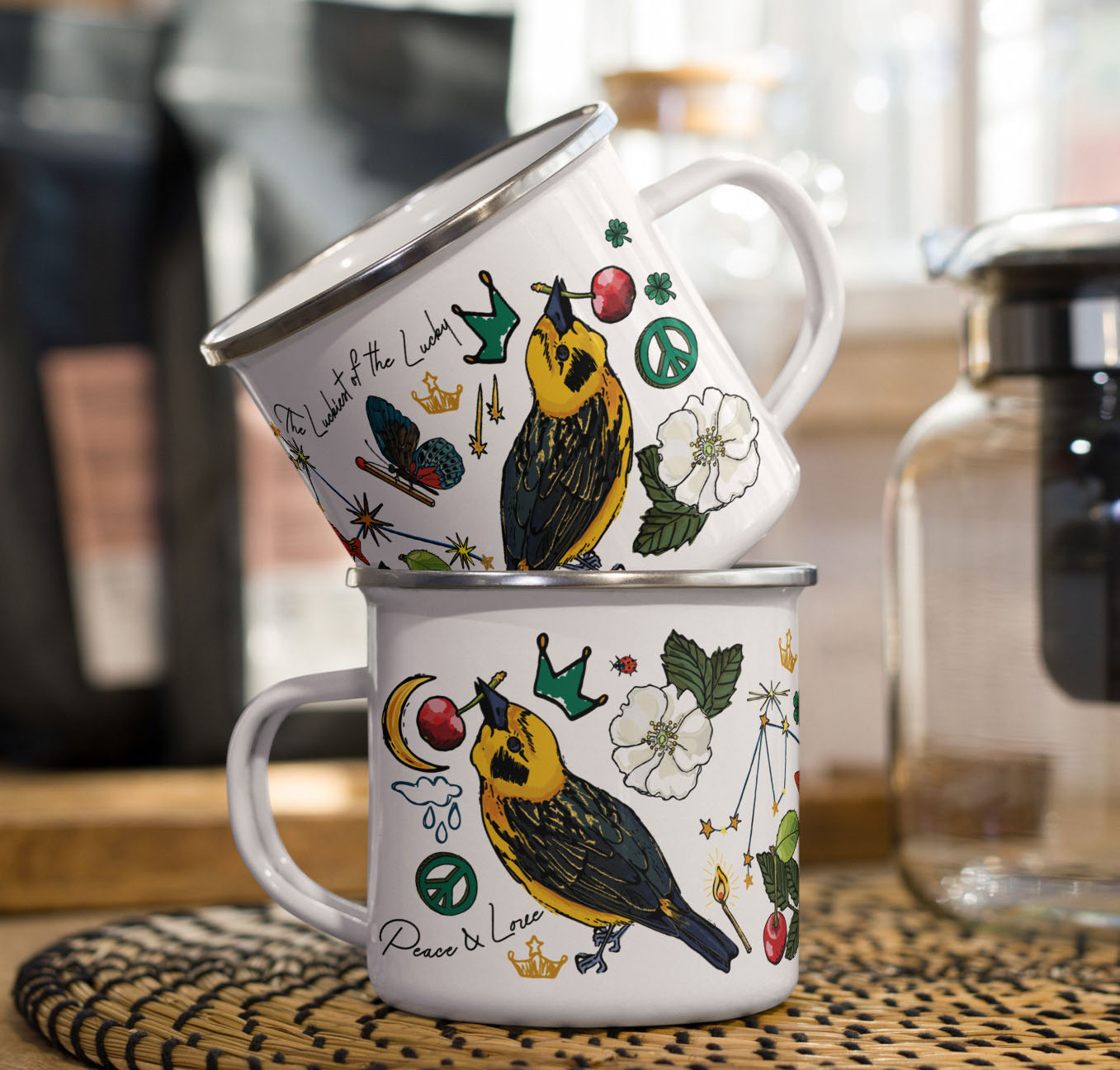 This is a photo of the Aquarius Stars enamel coffee mugs stacked on a kitchen counter sitting beside a coffee pot and bags of coffee.