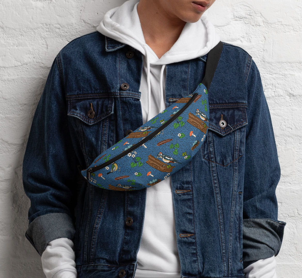 Pack worn in a sling bag style over a denim jacket and a white hoodie.