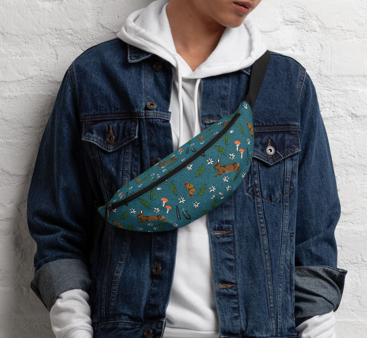 Pack worn in a sling bag style over a denim jacket and a white hoodie.