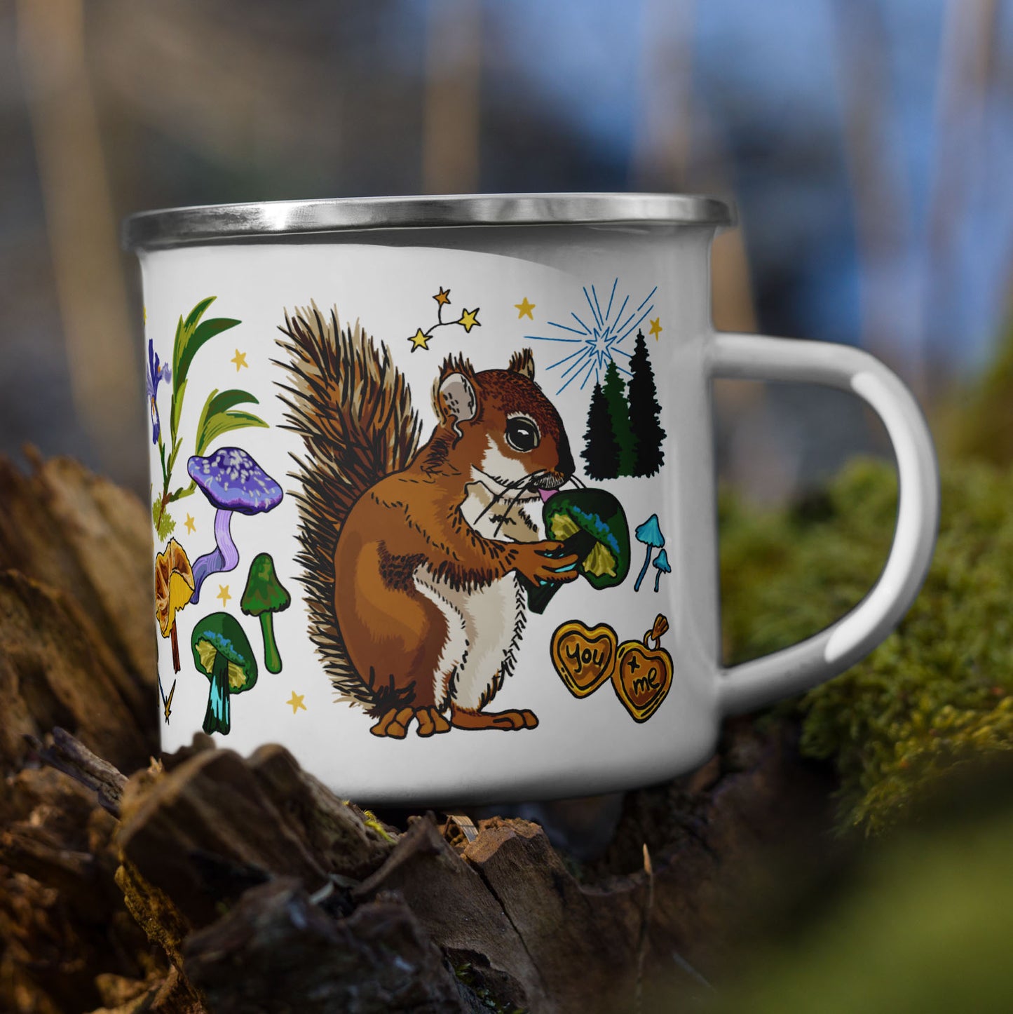 The Cyngus Stars Camp Mug sitting on a tree stump in the woods. The color of the enamel cup is white and the artwork is hand drawn illustrations of the Cygnus constellation, considered by sailors to be a good omen. The illustration includes a cheeky squirrel eating a green mushroom, pinecones, dragonflies, burning matches, oak leaves, acorns, iris flowers, pine trees, and other symbols of good fortune. The color palette is primarily forest greens, deep turquoise, purple and golden yellows.