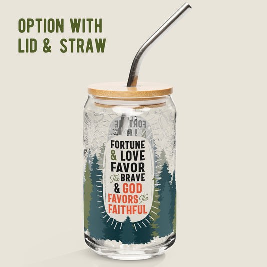 The Fortune, Love, and Faith glass tumbler with the bamboo lid and metal straw option on an ivory background. The artwork on the glass has a forest of pines coming up from the bottom. In the center there is an irregularly ivory oval with the phrase "Fortune & Love Favor the Brave & God Favors the Faithful". Surrounding that are icons of Appalachian good luck symbols. Symbols include rhododendron, lady bugs, horse shoes, salt, wishbone, stars, and four-leaf clover.
