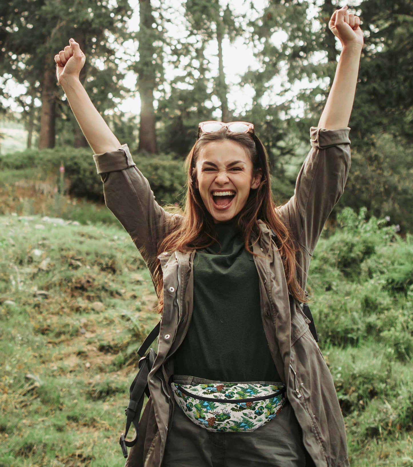 A photo of a woman hiking in the woods wearing the pack around her hips.