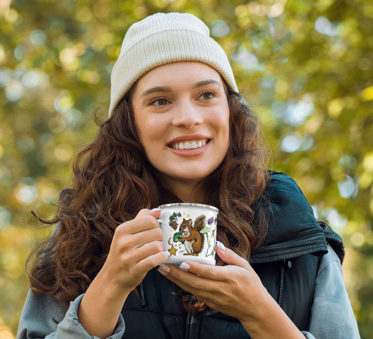 This image shows the camp coffee mug on a green organic shape at the top. The words "A cozy mug for scenic campsite fun" is laid out around the mug. This graphic overlays a photo of a woman relaxing in a hammock with her camp mug.