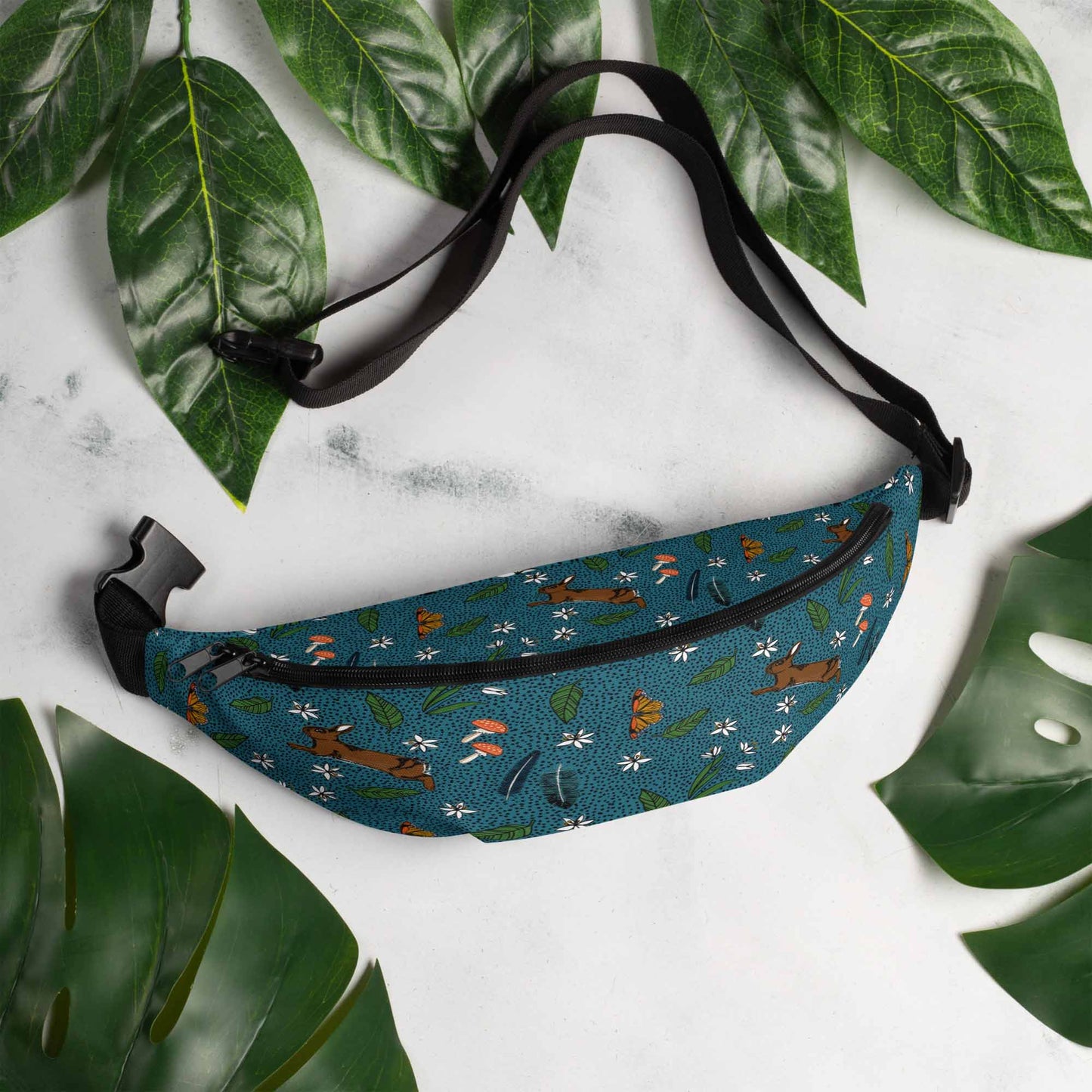 Rabbit meadow hip pack on a marble table surrounded by leaves.