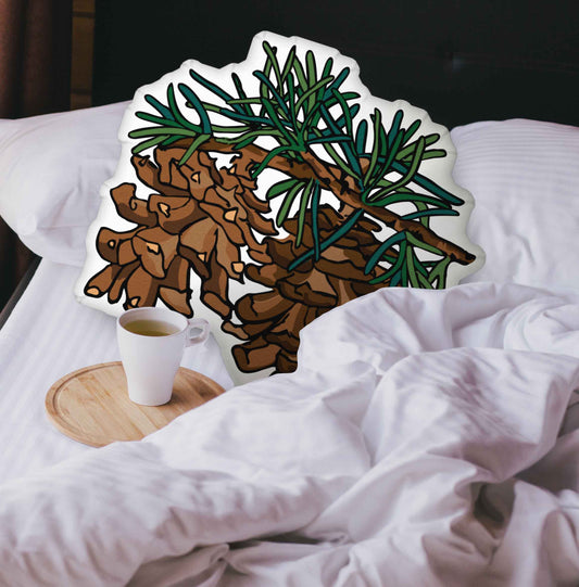 Pinecone-shaped pillow nestled in an unmade bed. There is a cup of coffee sitting on a wooden tray.