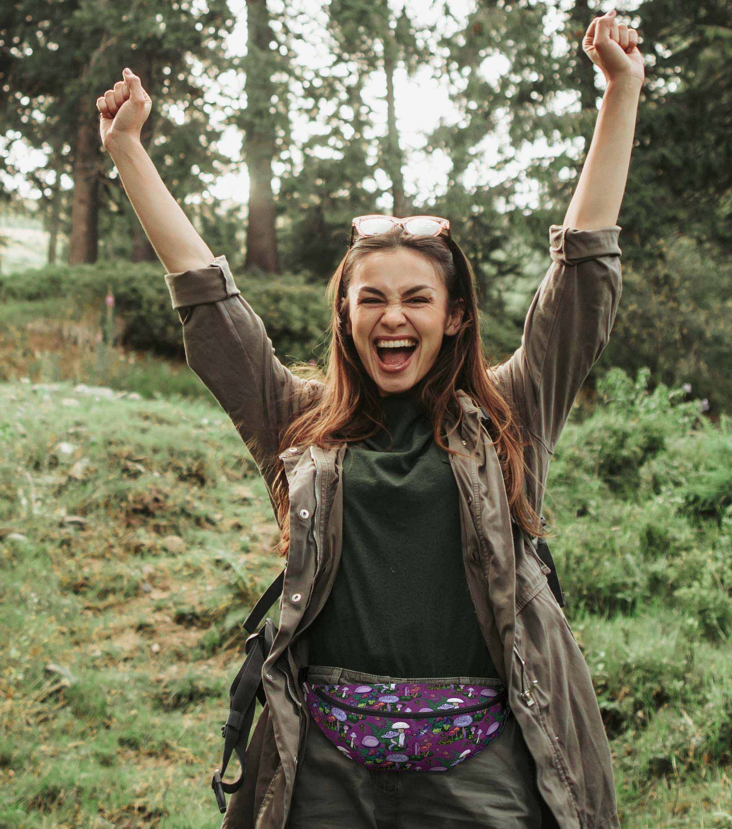 A photo of a woman hiking in the woods wearing the pack around her hips.