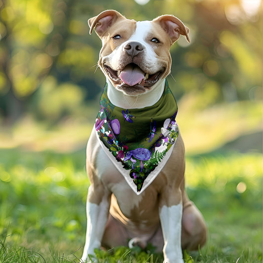 Happy dog wearing the red mushroom bandana around his neck. He's sitting outside in the grass.