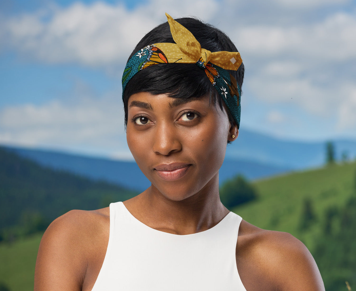 This is an image of a woman wearing the bandana as a headband. There is a mountain view behind her.