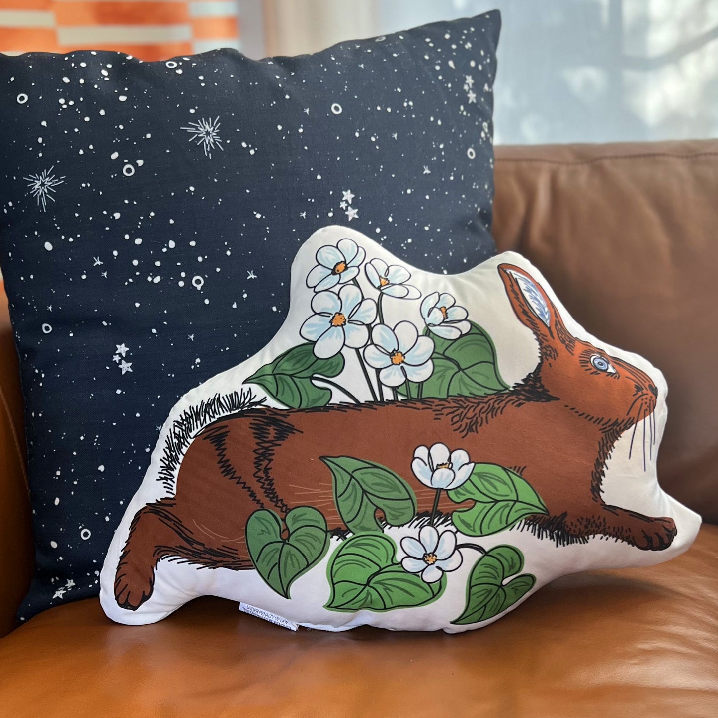 This is a photo of the rabbit pillow on a leather couch.