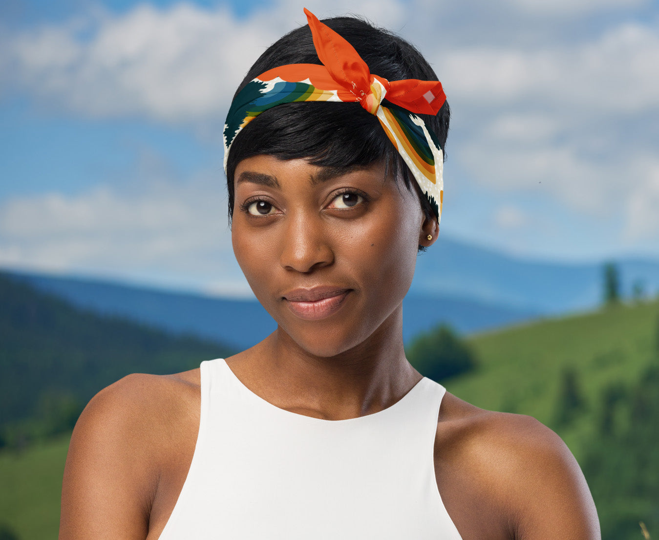 This is an image of a woman wearing the bandana as a headband. There is a mountain view behind her.