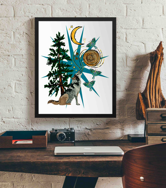 This is a photograph of the framed Wild Wolf Moon & Luna Moths art print hanging on a white brick wall. Below it, there is a wood. The desk has a camera, laptop, and wood sculpture on it.