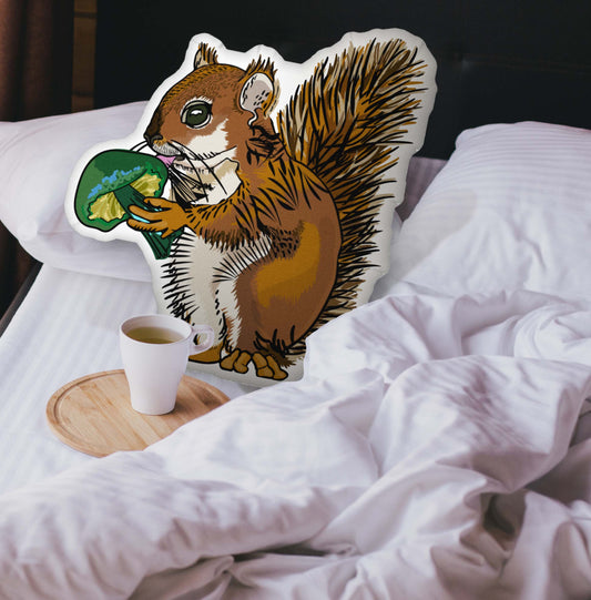 The squirrel and mushroom pillow nestled in an unmade bed. There is a cup of coffee sitting on a wooden tray.