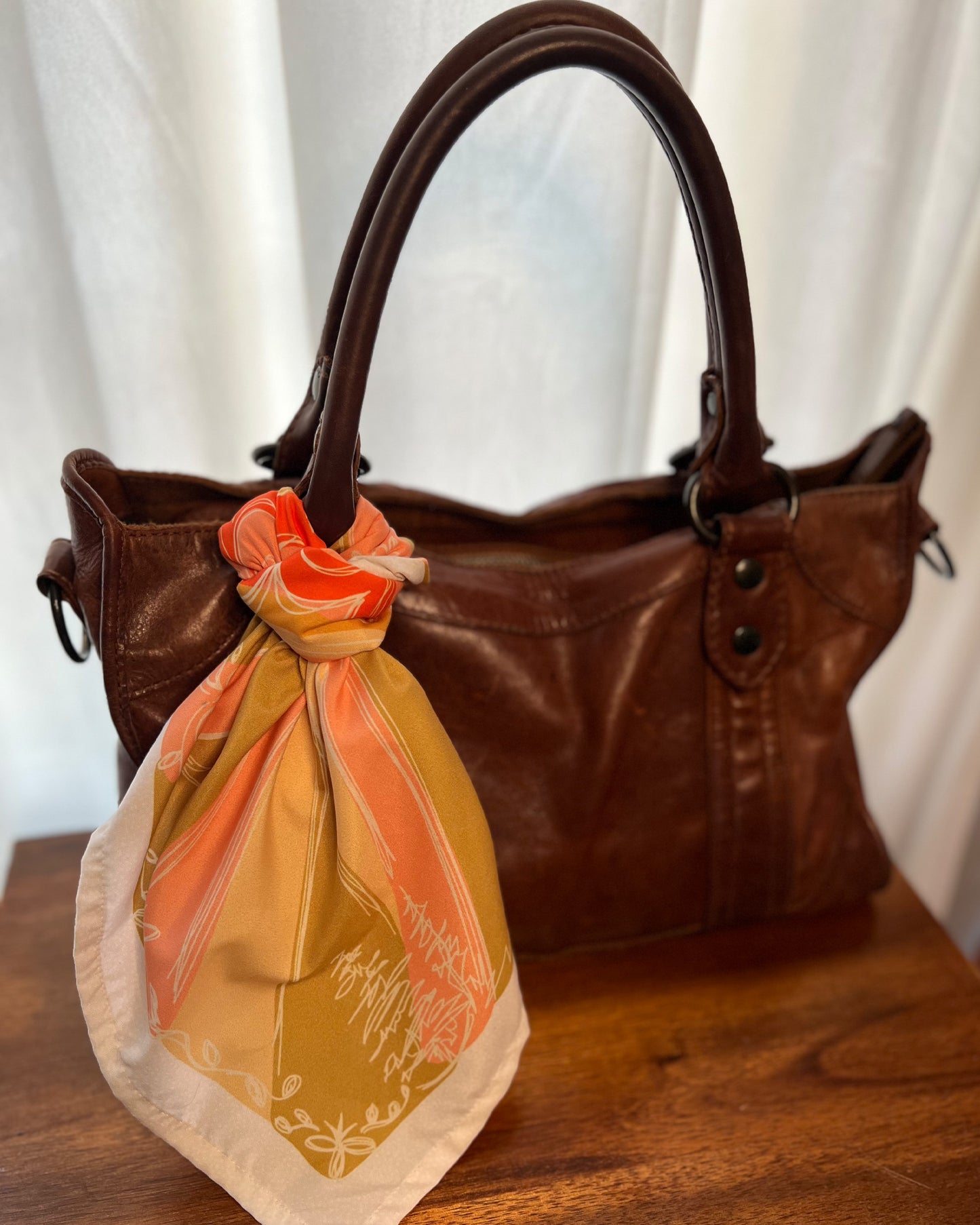 The terracotta sun bandana styled on a leather purse.