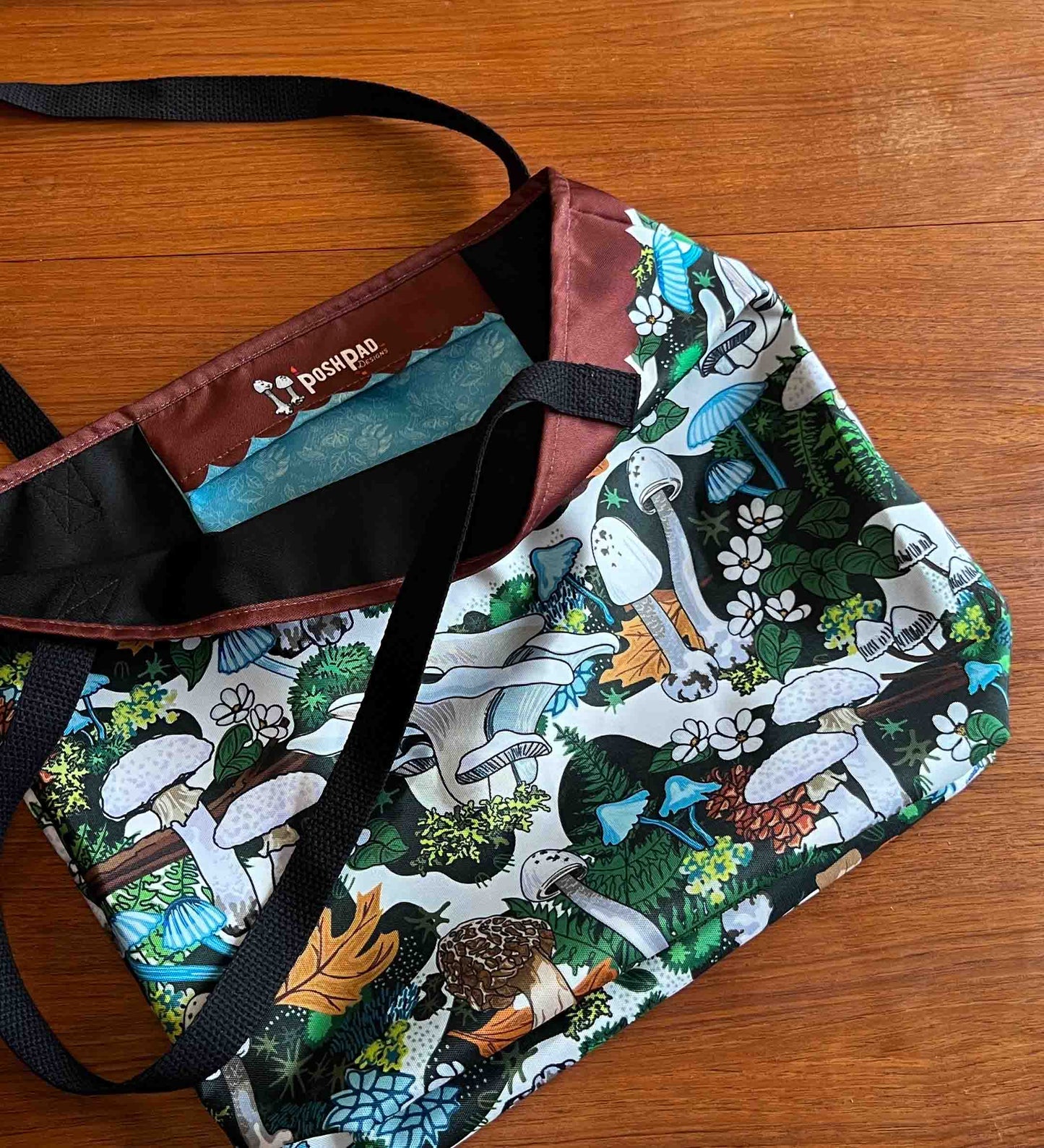 The tote is lying open on a wooden table. It shows the inside pocket.