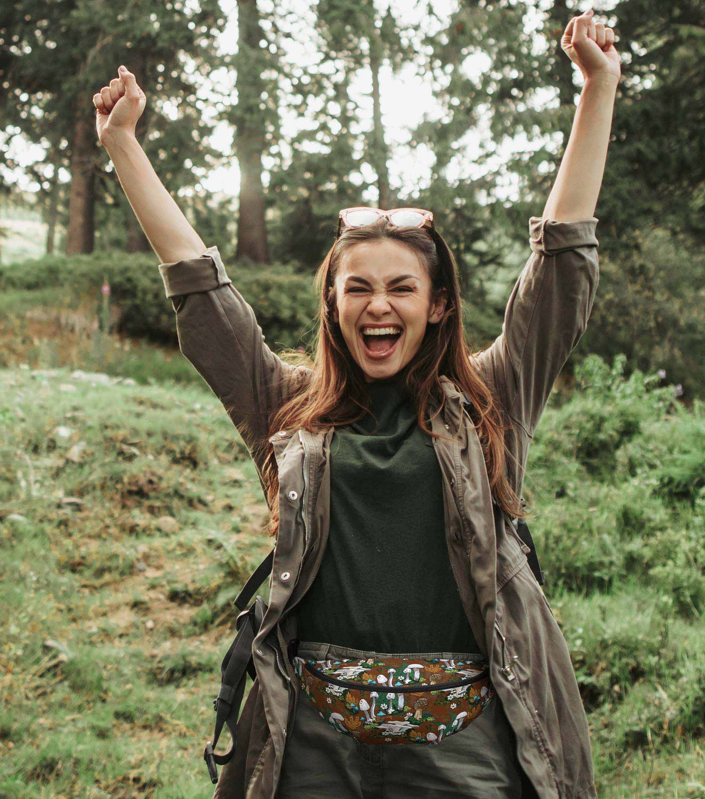 A photo of a woman hiking in the woods wearing the pack around her hips.