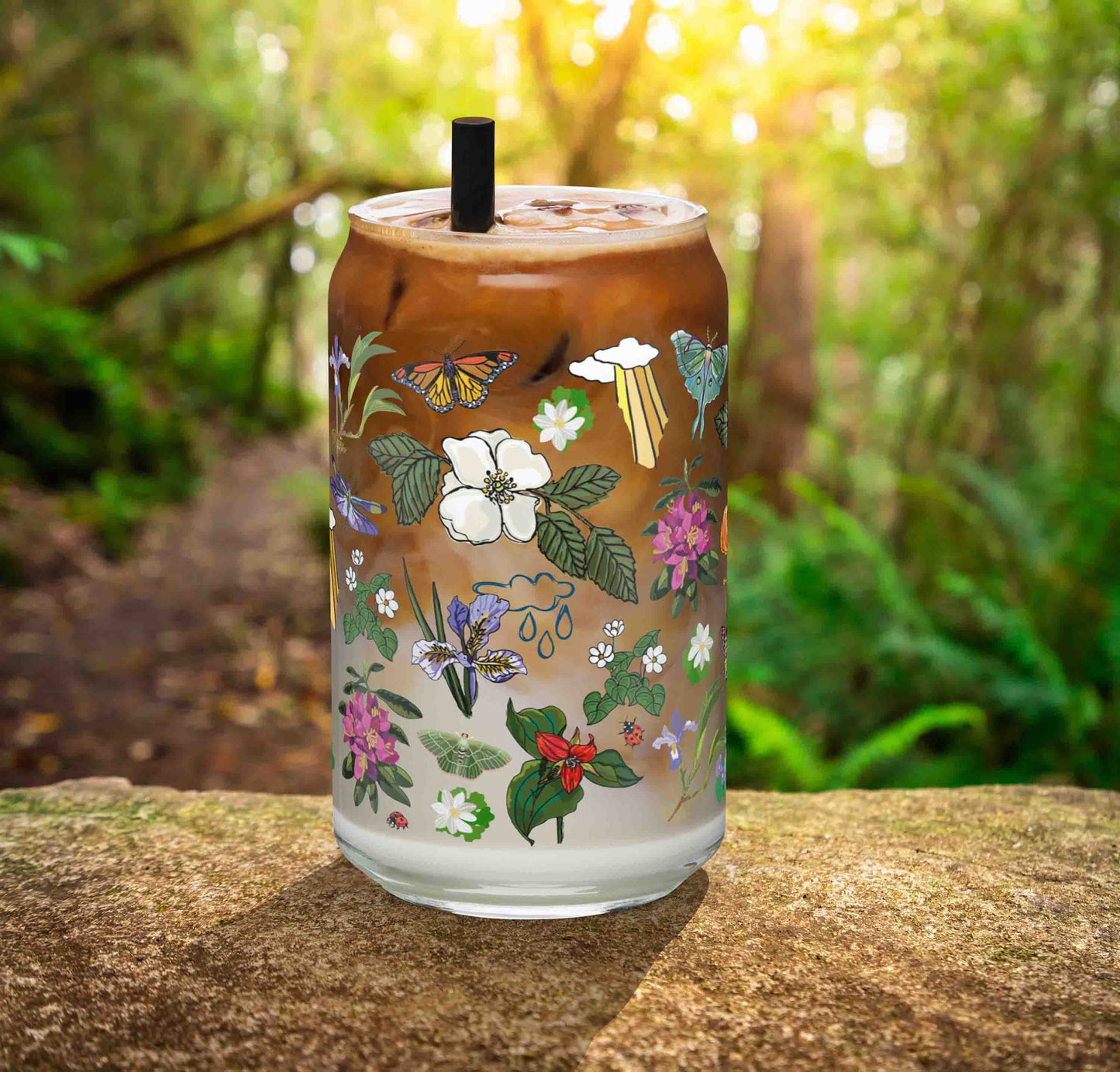 This is a photo of the glass containing an iced latte. It's sitting on a rock in the woods.