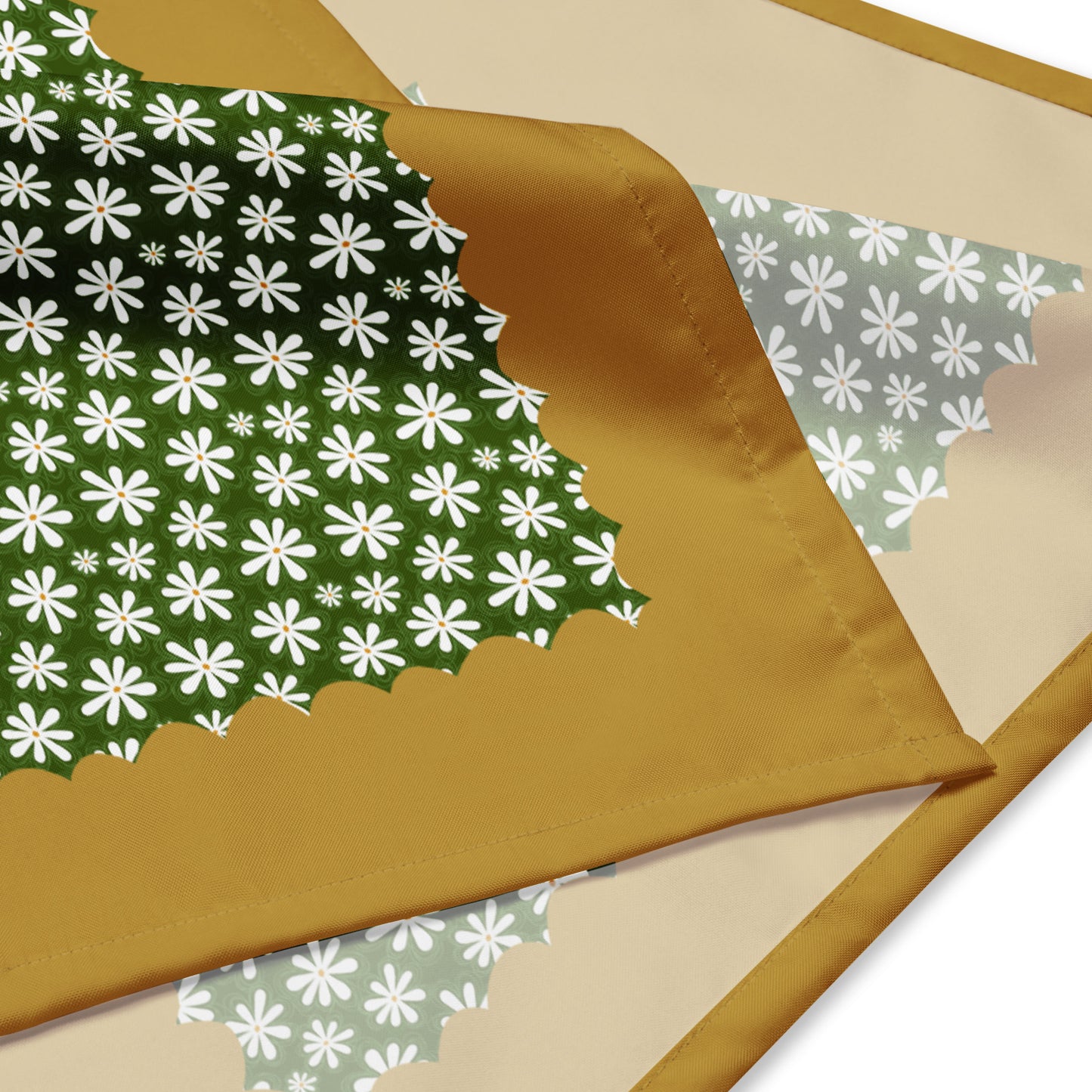 This is a close-up shot of the corner of the Daisy Flower bandana. It shows the detailed of the white flowers on a green background. The edges around it is golden yellow with a scalloped inside edge.