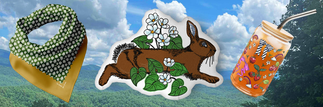 A landscape photo of the Great Smoky Mountains with three Posh Pad products overlaid. The products are the Daisy Bandana, The Rabbit Meadow Shaped Pillow, and the Bows and Berries Can-shaped Glass.