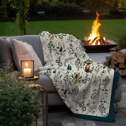Fierce, Feral, and Free sherpa blanket draped over a couch by a fire pit in an outdoor setting.