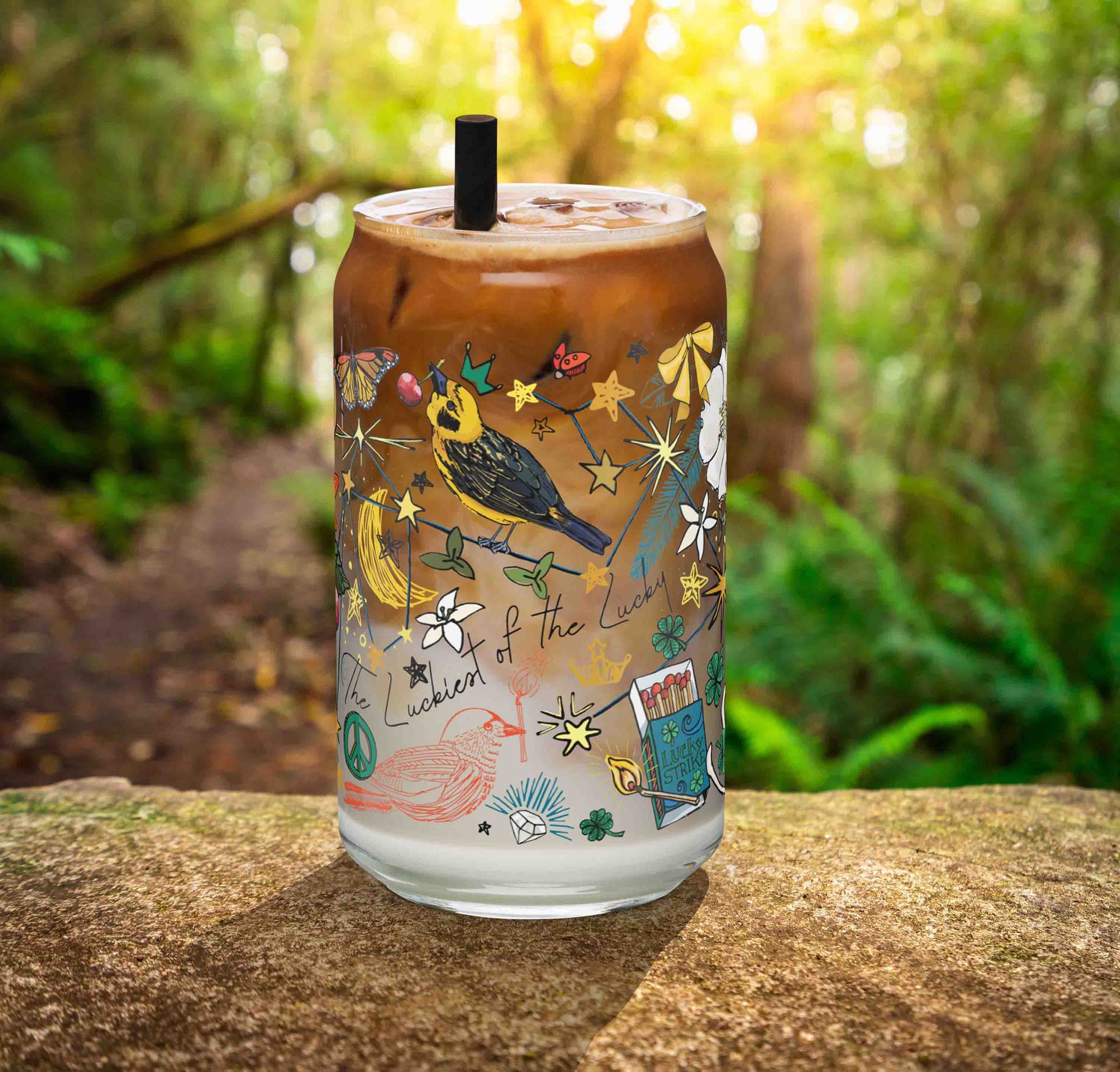 This is a photo of the glass containing an iced latte. It's sitting on a rock in the woods.