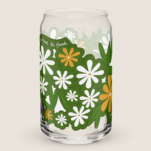 Image of the glass tumbler. The artwork has illustrations of white and yellow daisies, leaves, and the phrase "Do Good. Be Good." woven between them. These illustrations have an organic green shape around them.