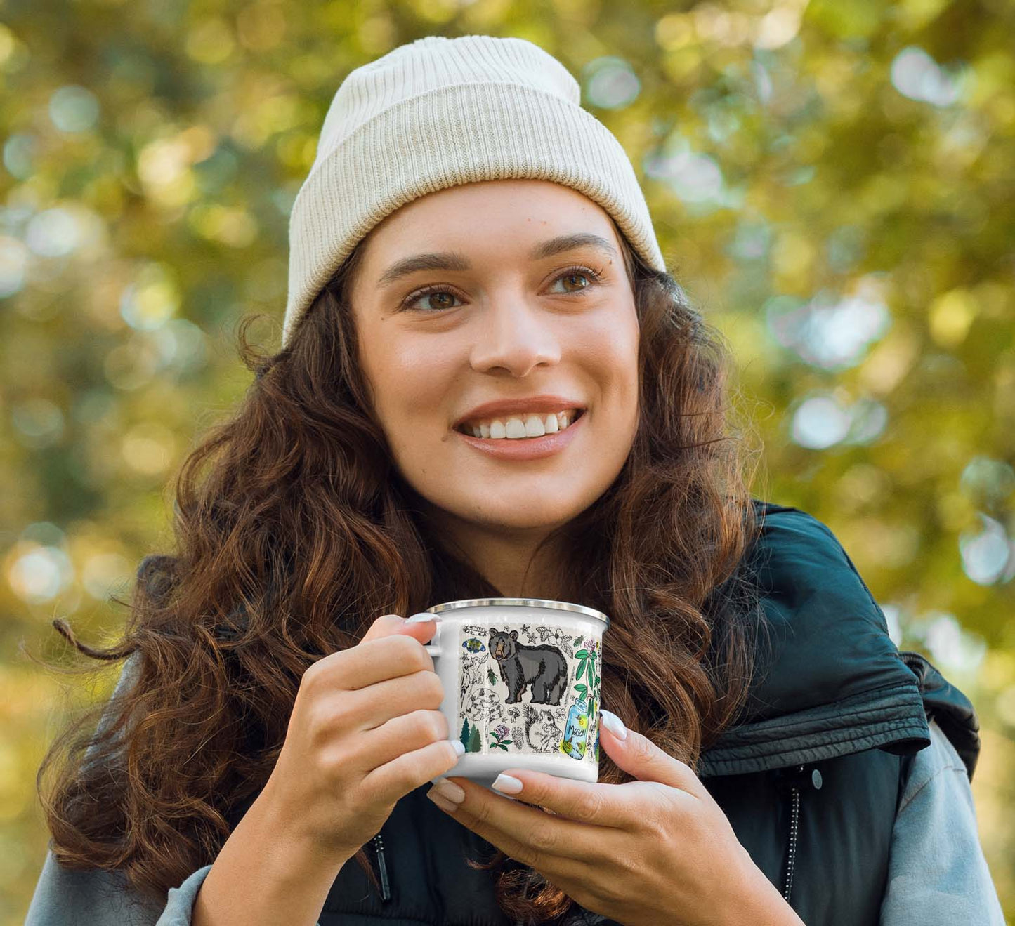Woman hiker holding a mug outdoors with blurred forest in the background