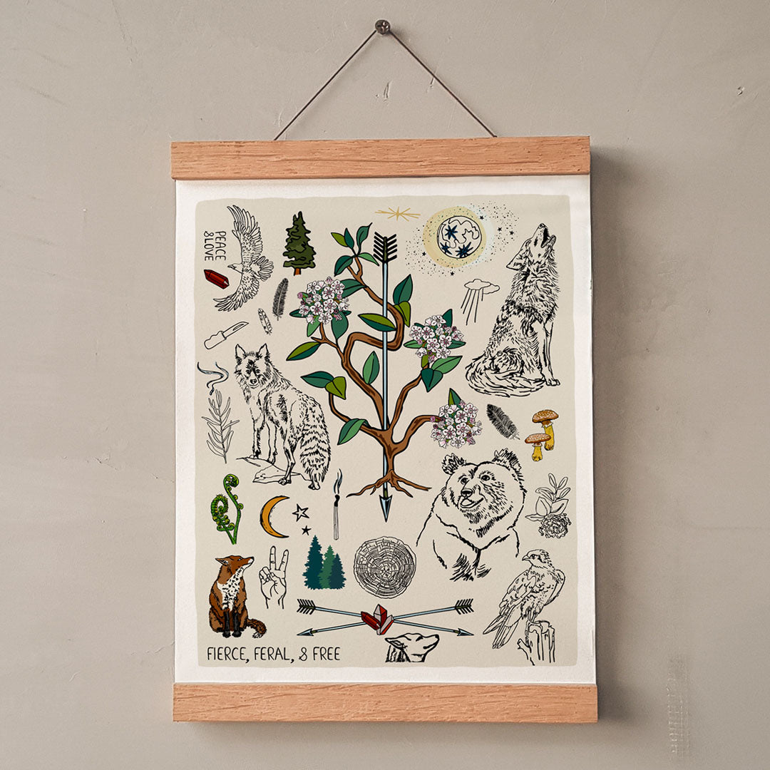 Fierce, Feral, and Free art print poster hung in a wooden wall hanger. The artwork has bears, wolves, birds, forest, a full moon, a crescent moon, crossed arrows, mushrooms, burning sage, and a camp knife. 
