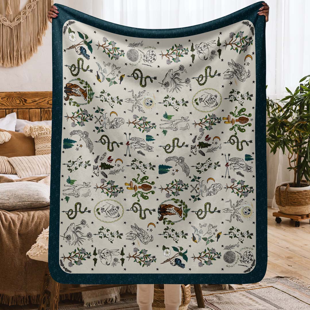 This image shows the size. It's a person holding up the Fierce, Feral, and Free sherpa blanket in a cozy boho-style apartment.