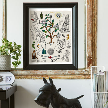 Fierce, Feral, and Free art print poster framed in a thick black frame in a home office. The artwork has bears, wolves, birds, forest icons, a full moon, a crescent moon, crossed arrows, mushrooms, burning sage, matches, and a camp knife. 