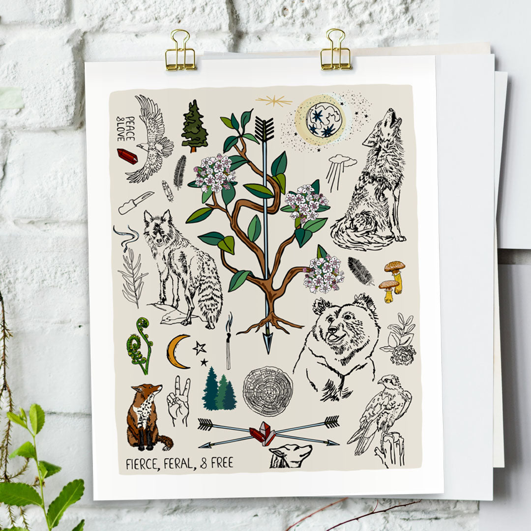 Fierce, Feral, and Free art print poster hung with gold clips on a white brick wall. The artwork has bears, wolves, birds, forest, a full moon, a crescent moon, crossed arrows, mushrooms, burning sage, matches, and a camp knife. 