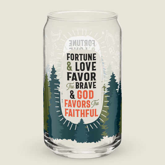 The Fortune, Love, and Faith glass tumbler on an ivory background. The artwork on the glass has a forest of pines coming up from the bottom. In the center there is an irregularly ivory oval with the phrase "Fortune & Love Favor the Brave & God Favors the Faithful". Surrounding that are icons of Appalachian good luck symbols.  Symbols include rhododendron, lady bugs, horse shoes, salt, wishbone, stars, and four-leaf clover. The color palette is a mix of earthy greens, ivory, and accents of red.