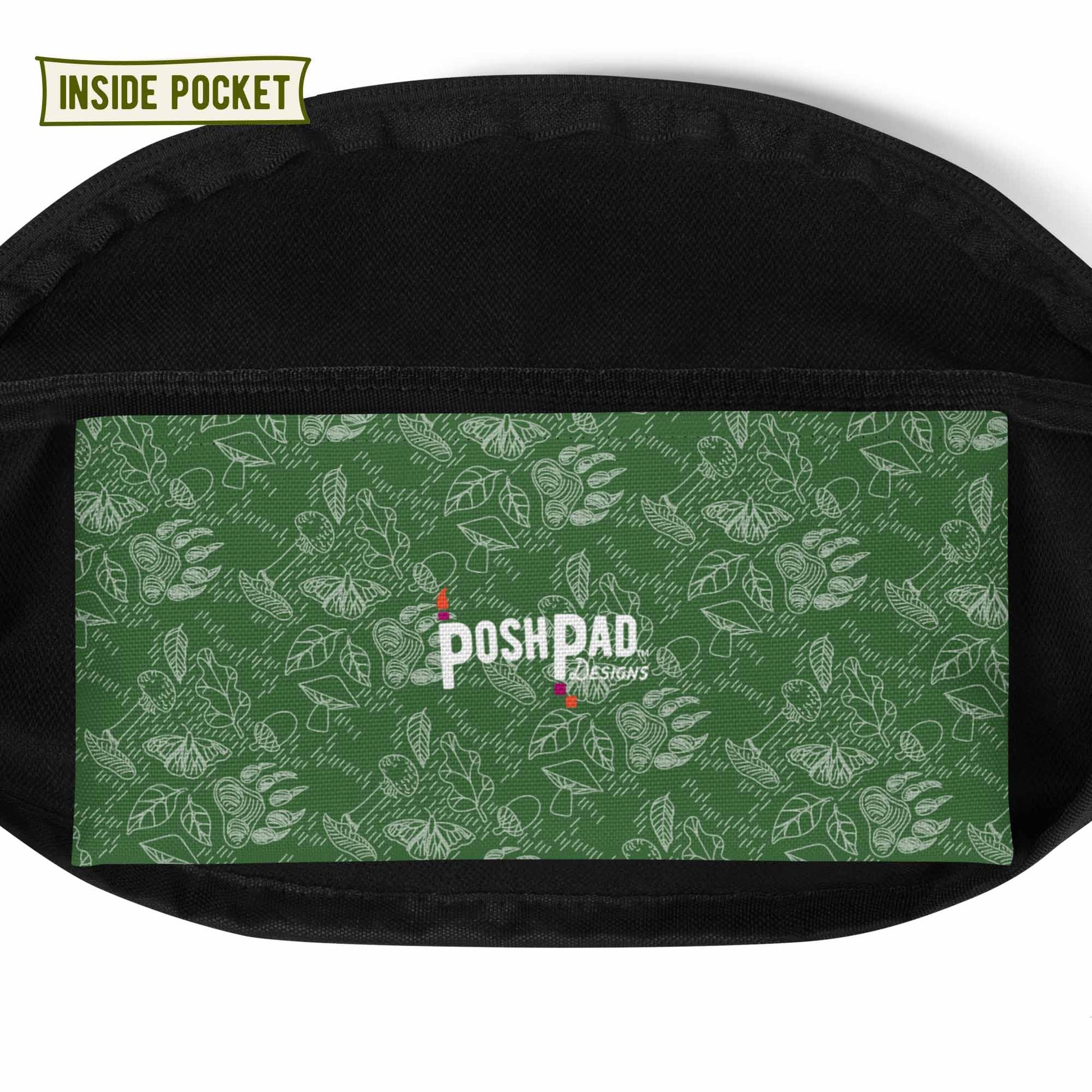 View of the inside pocket. It has a white pattern of bear paws, mushrooms, butterflies, and leaves on a green background. The Posh Pad logo is in the middle.
