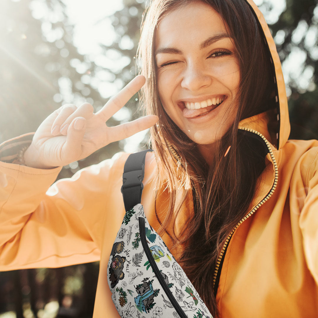 A photo of a woman hiking in the woods wearing the pack as a sling bag over her shoulder.