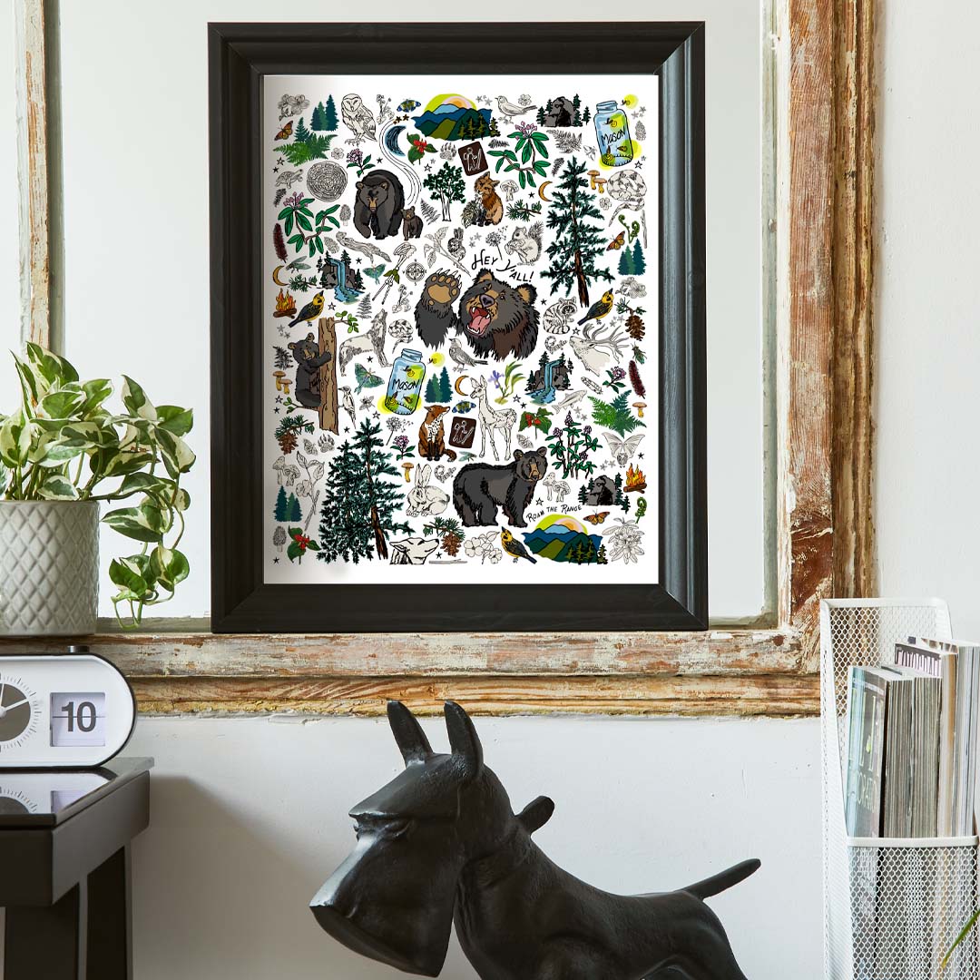 The Mountain Hikes art pPrint poster framed in a heavy black frame and hung inside a vintage frame above a desk.