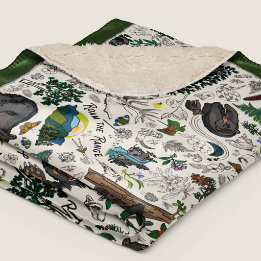 Mountain Adventures Faux Fur Sherpa blanket folded and lying on an ivory background.
