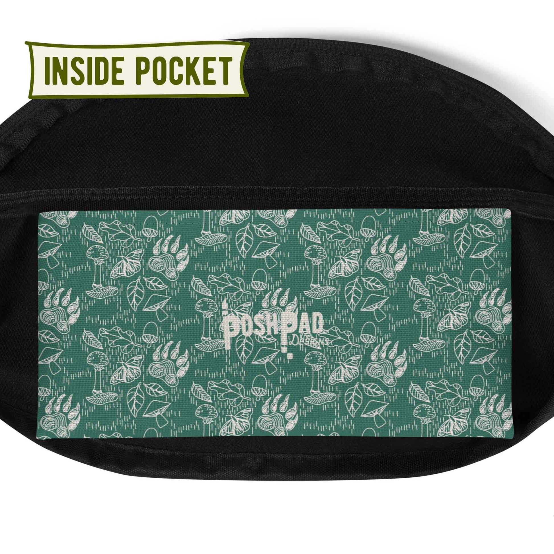 View of the inside pocket. It has a white pattern of bear paws, mushrooms, butterflies, and leaves on a green background. The Posh Pad logo is in the middle.