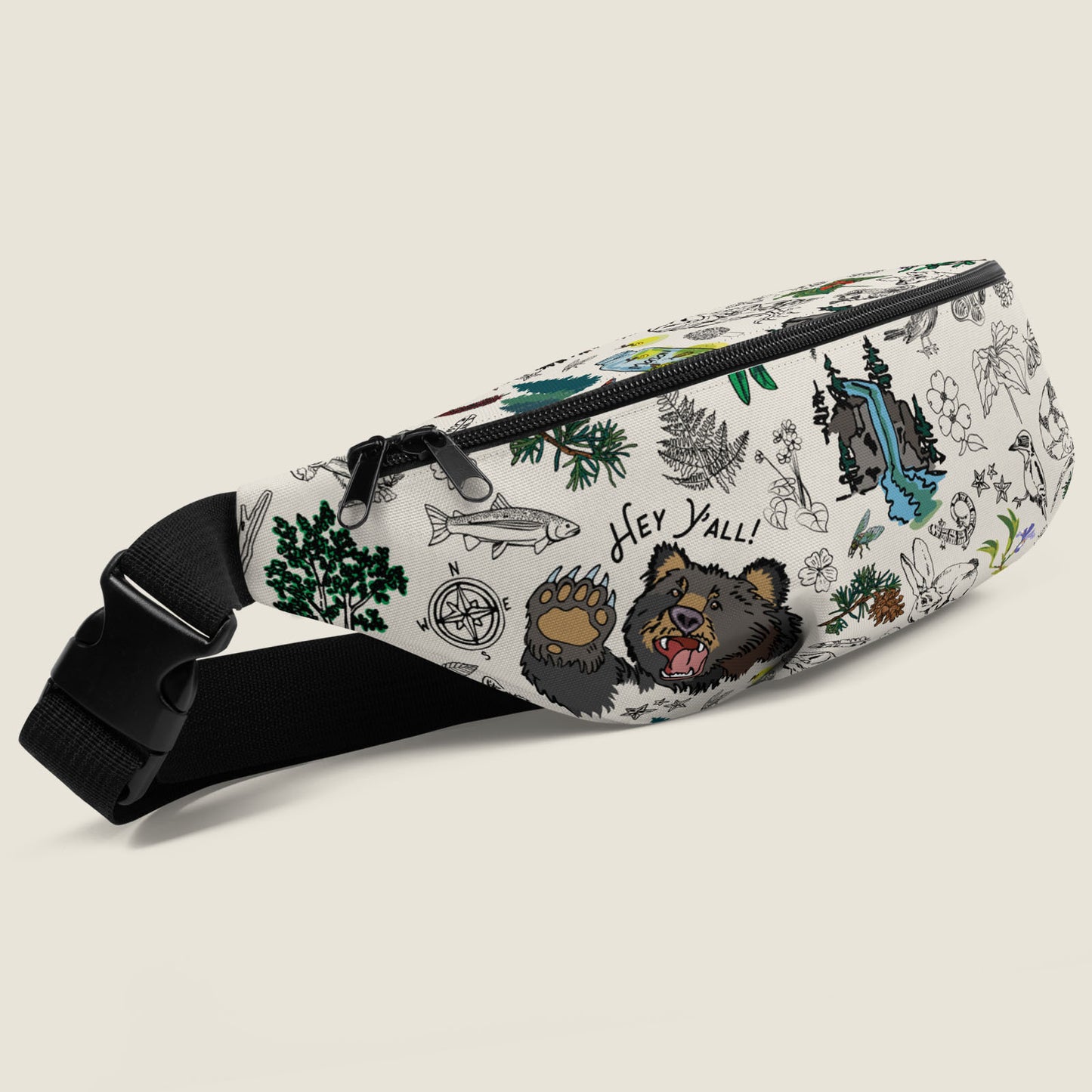 Three quarter view of the Mountain Hikes fanny pack with a pattern design that includes bears, mountains, ferns, pine trees, waterfalls, and other wilderness icons.