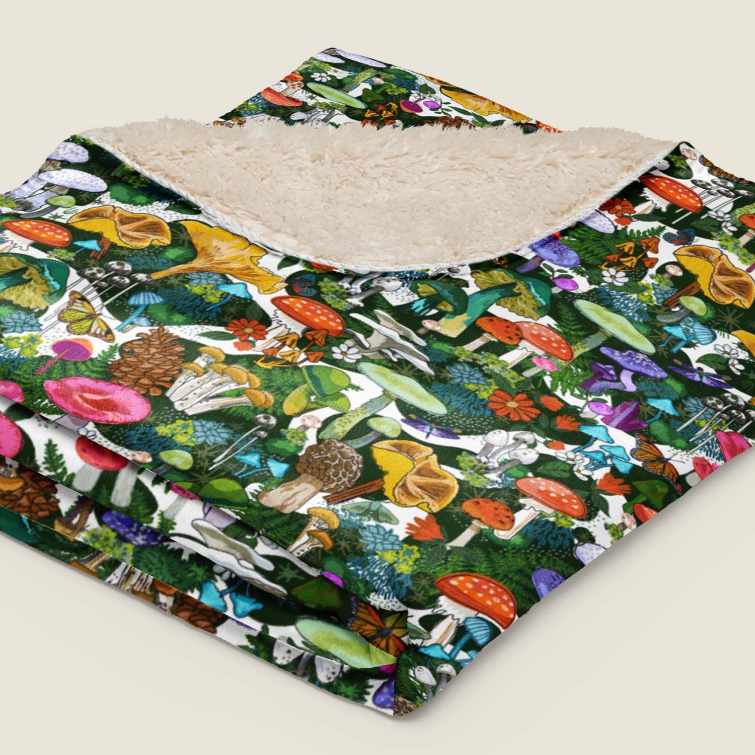 Wild Mushrooms Faux Fur Sherpa blanket folded and lying on an ivory background.