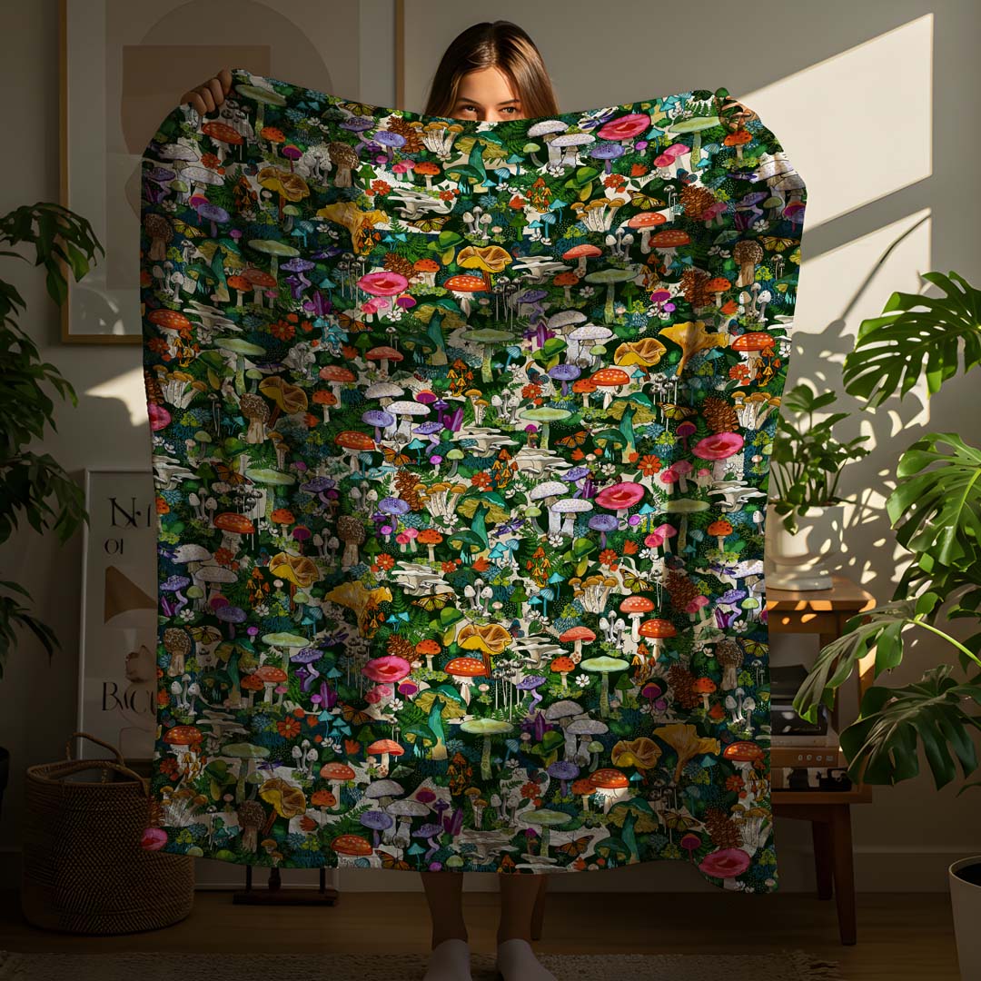 This image shows the size. It's a person holding up the Wild Mushroom sherpa blanket in a cozy boho-style apartment.