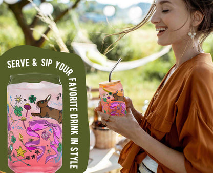 This is a photo of the glass with ice and a pink drink in it. It's laid over an organic green shape with the words "Serve & sip your favorite drink in style" written around the glass. This is laid over a photo of a woman holding the glass at a picnic.