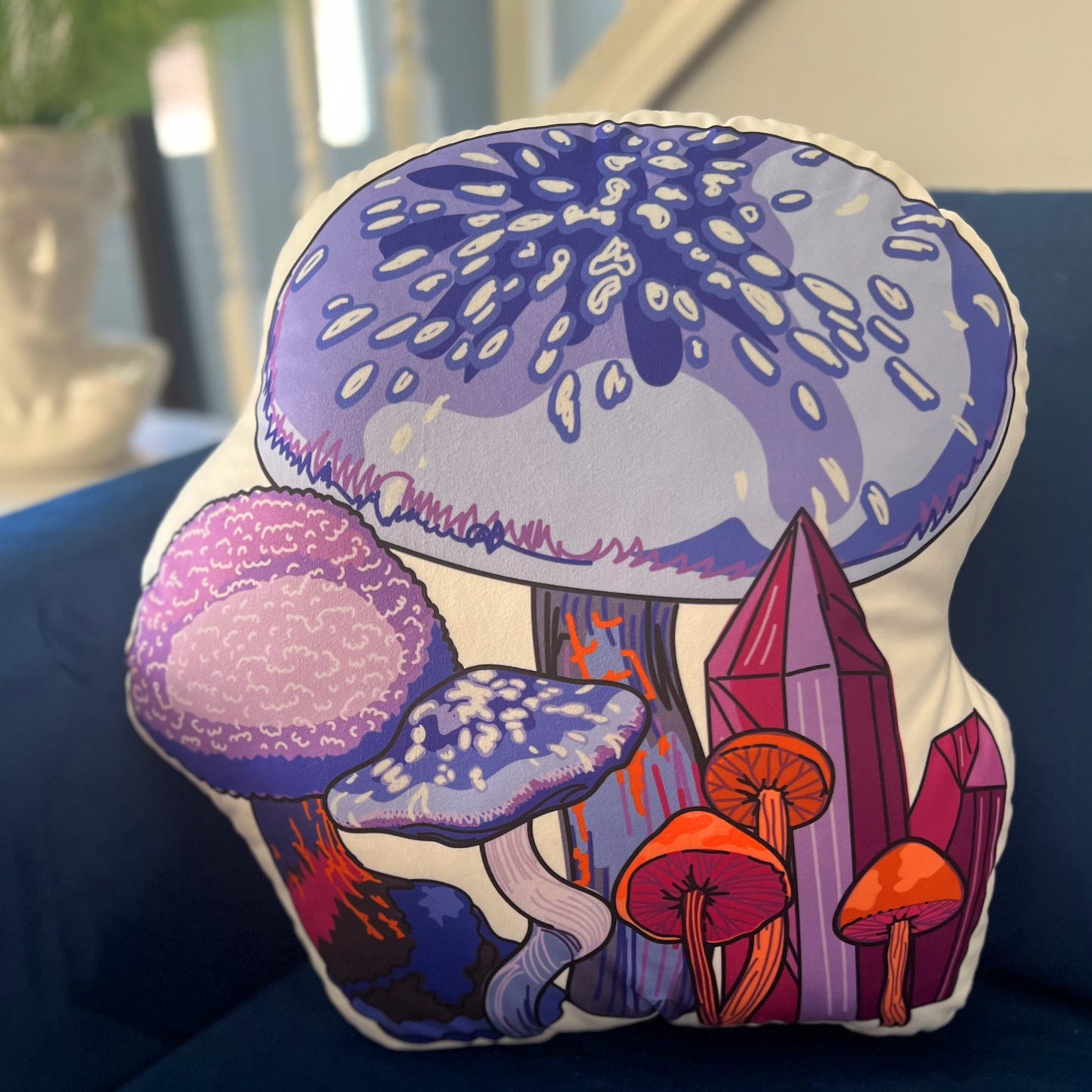This is a photo of the purple mushroom pillow sitting on a blue couch.