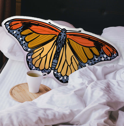 A velvety red and gold butterfly-shaped pillow nestled into a cozy, layered bed. The plush texture and hand-drawn bohemian details add a warm, nature-inspired touch to your space.