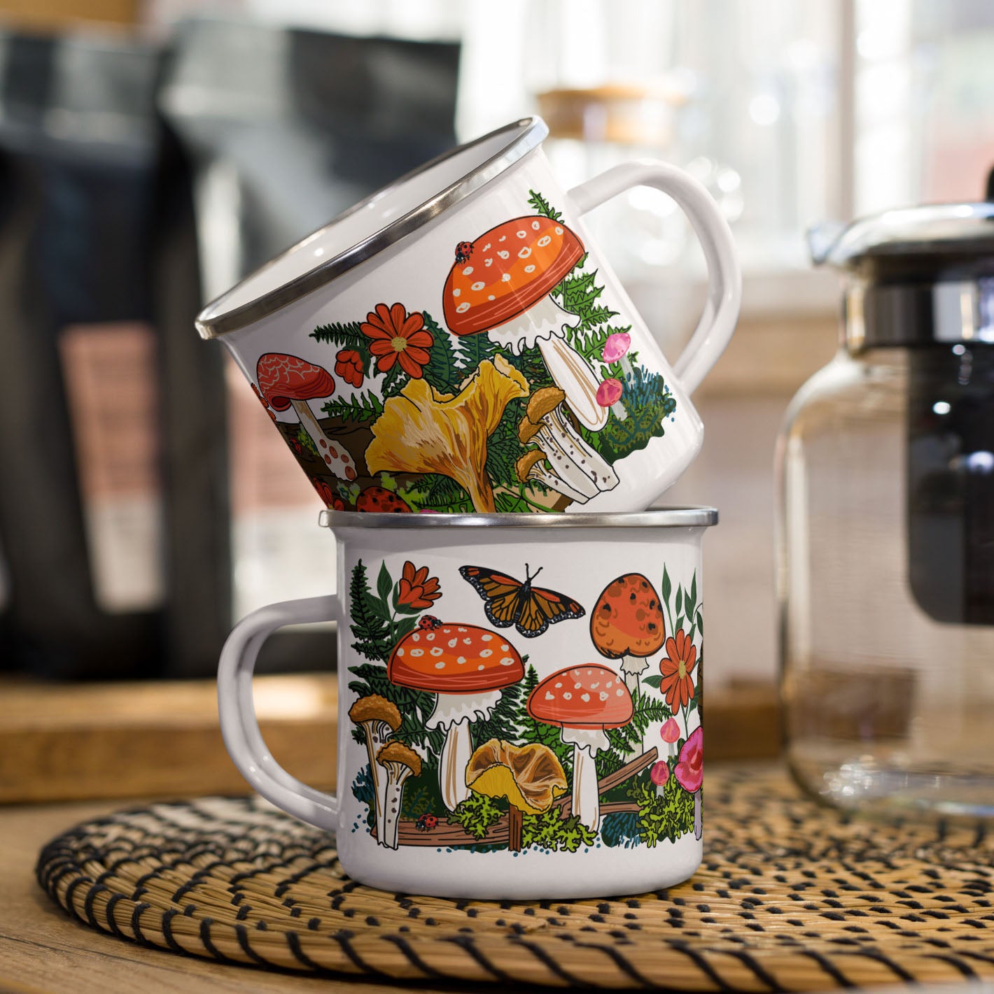 Two stacked red mushroom enamel coffee cups on a kitchen counter.