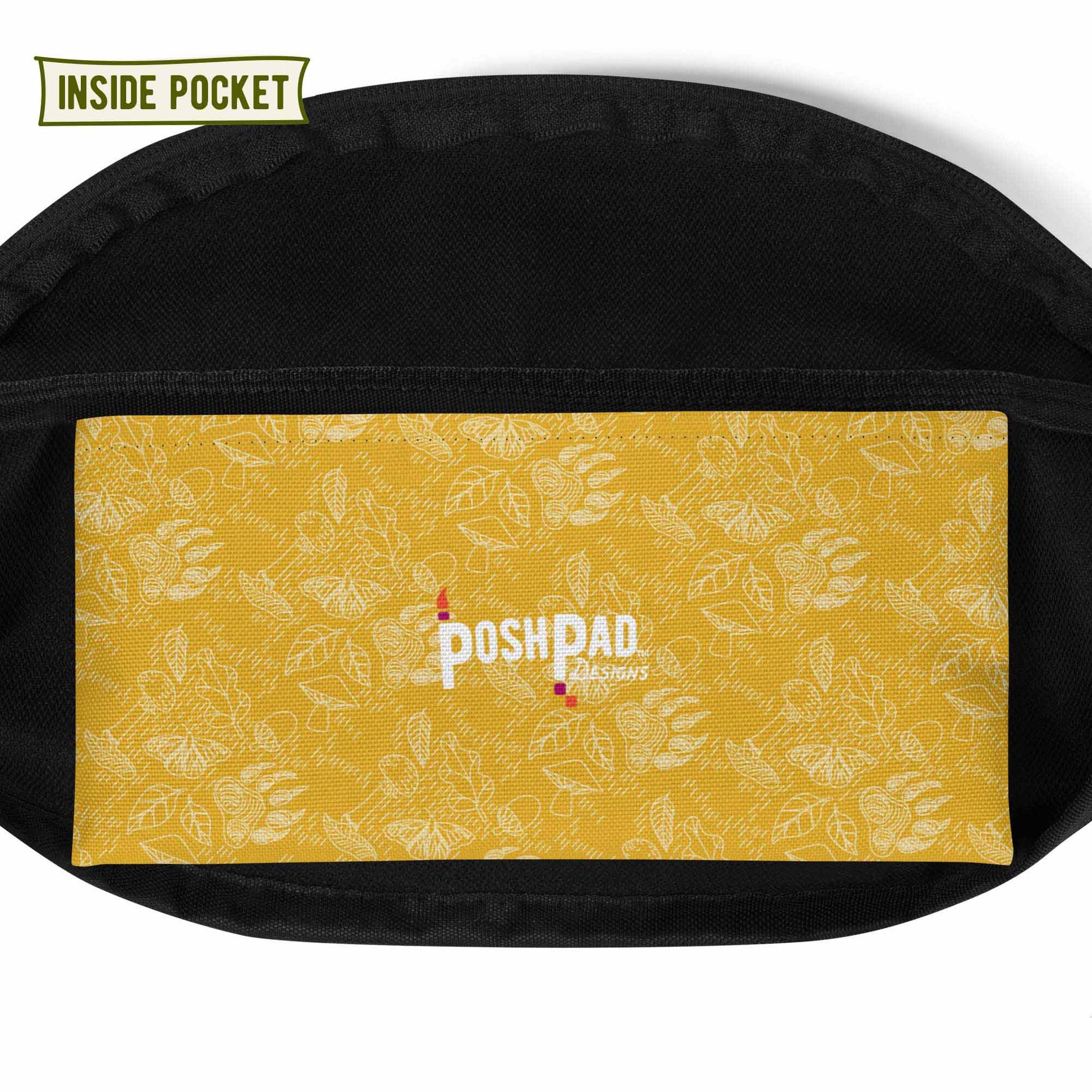 View of the inside pocket. It has a white pattern of bear paws, mushrooms, butterflies, and leaves on a yellow background. The Posh Pad logo is in the middle.