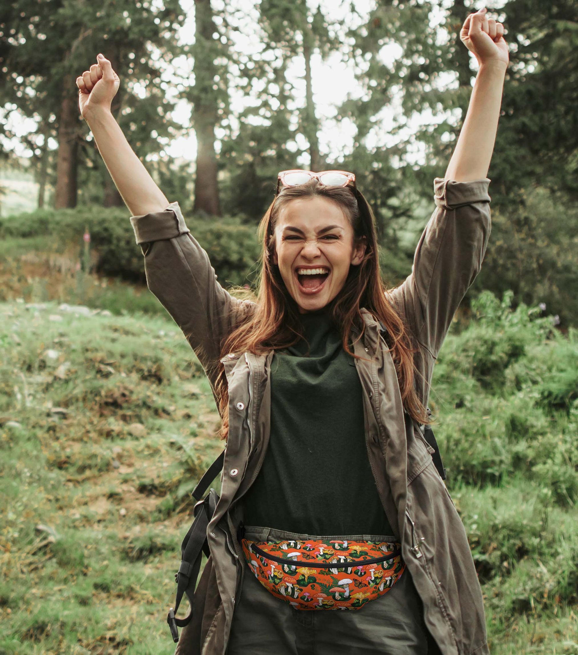 A photo of a woman hiking in the woods wearing the pack around her hips.