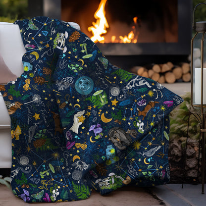 Under the Stars sherpa blanket draped over a couch by a fire pit in an outdoor setting.
