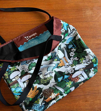 The tote is lying open on a wooden table. It shows the inside pocket.
