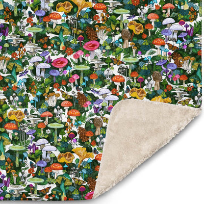 Close-up of the corner of the Wild Mushroom blanket. The illustrations include wild mushrooms of all kinds nestled in moss and the small flowers. There are also butterflies and moths in the illustration.